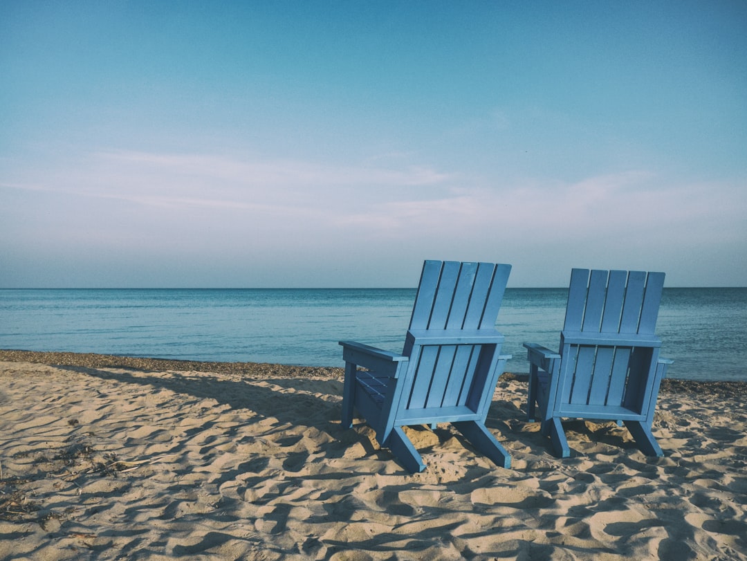 Illustration: two blue beach chairs near body of water
